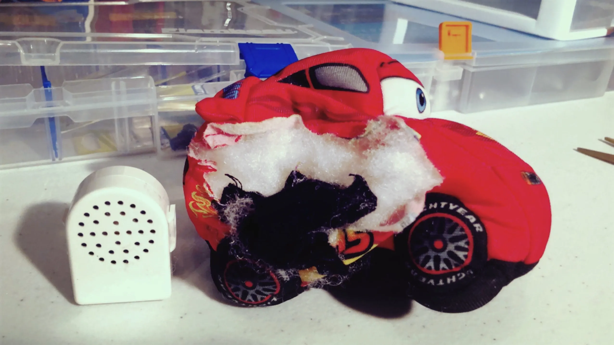 A cut-open stuffed toy car with its sound module sitting next to it